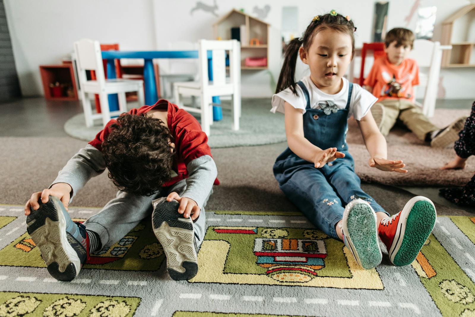 Young children stretching and exercising together in a kindergarten classroom.