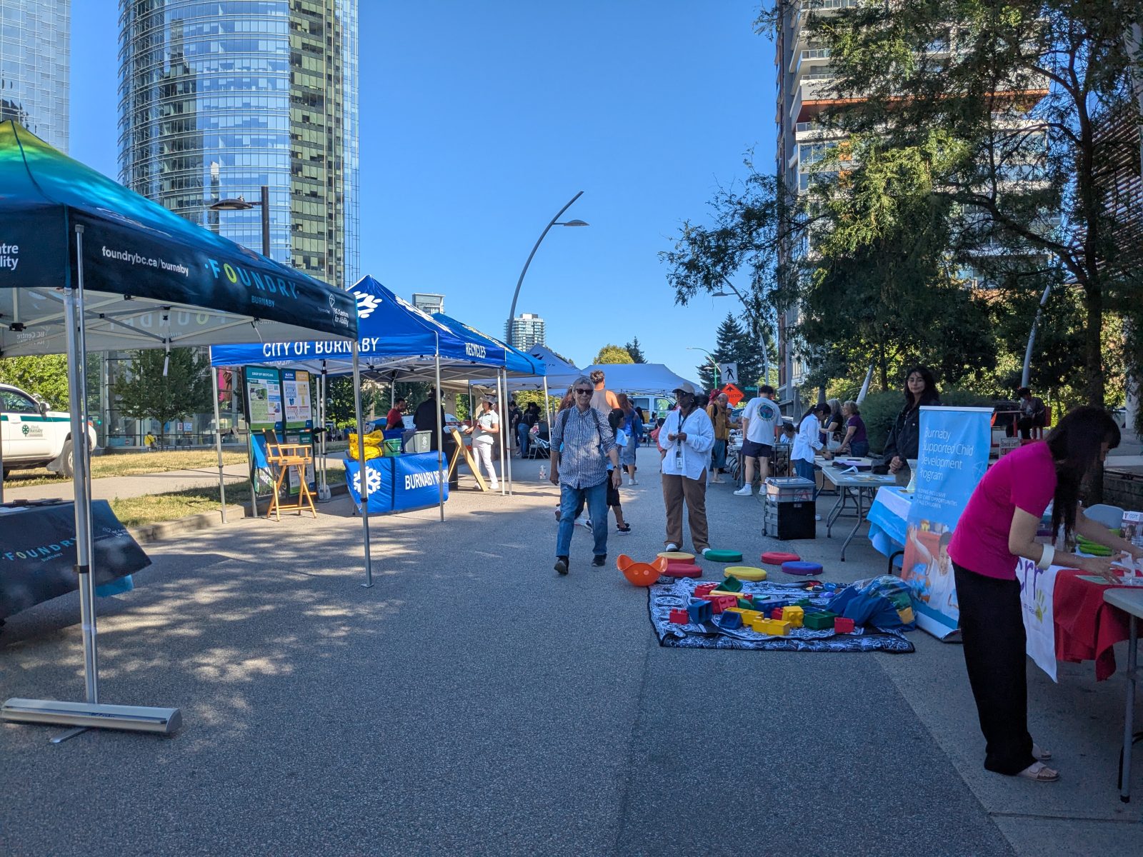 Children and parents browsing, reading and enjoying free books at Literacy Now Burnaby table at South Burnaby Summer Social 2025 event.
