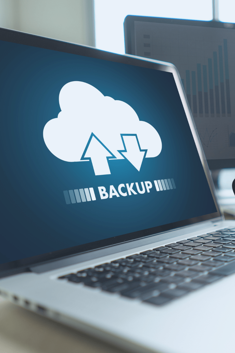 A laptop screen with an icon of a cloud with arrows indicating transfer of files for a backup
