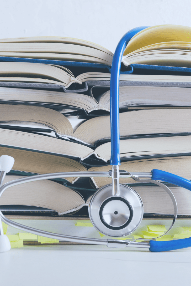 A stack of books topped with a stethoscope, symbolizing learning, healthcare, and accessible health knowledge.