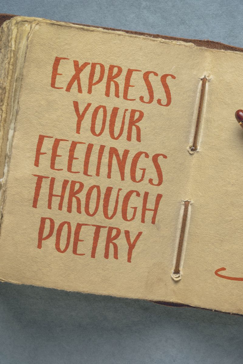 Book opened with the phrase Express your feelings through poetry in red. Red pen on top of the book.